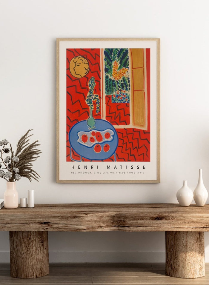 Artistic depiction of a still life scene with a blue table, vase, and fruit, by Henri Matisse. Red Interior, Still Life on a Blue Table by Henri Matisse is a 1947 modern art print featuring bold color, expressive interiors, floral still life details, and iconic French design.