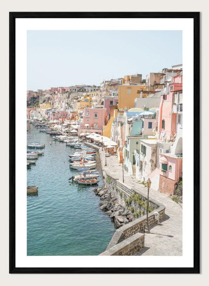 Colorful coastal town with boats docked along a waterfront. Colorful Italian Harbor by Henrike Schenk is a coastal photography print featuring pastel waterfront architecture, fishing boats, turquoise waters, and Mediterranean charm.