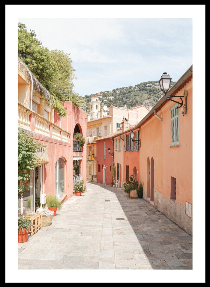 Tiled street with colorful buildings and greenery under a clear blue sky. Colorful Old Town Street by Henrike Schenk is a European travel photography print featuring Mediterranean architecture, pastel buildings, and street wall art.
