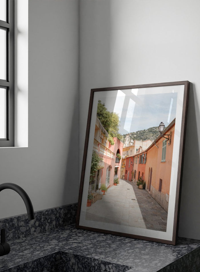 Tiled street with colorful buildings and greenery under a clear blue sky. Colorful Old Town Street by Henrike Schenk is a European travel photography print featuring Mediterranean architecture, pastel buildings, and street wall art.