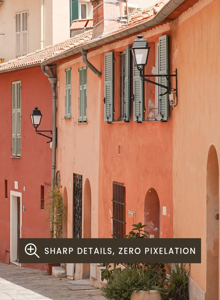 Tiled street with colorful buildings and greenery under a clear blue sky. Colorful Old Town Street by Henrike Schenk is a European travel photography print featuring Mediterranean architecture, pastel buildings, and street wall art.