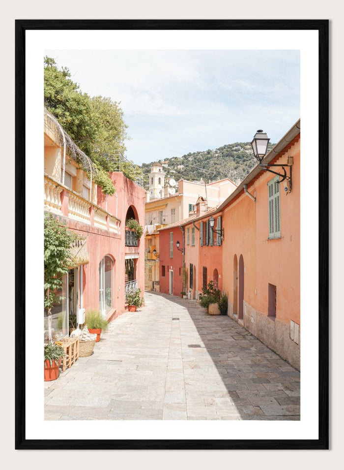 Tiled street with colorful buildings and greenery under a clear blue sky. Colorful Old Town Street by Henrike Schenk is a European travel photography print featuring Mediterranean architecture, pastel buildings, and street wall art.