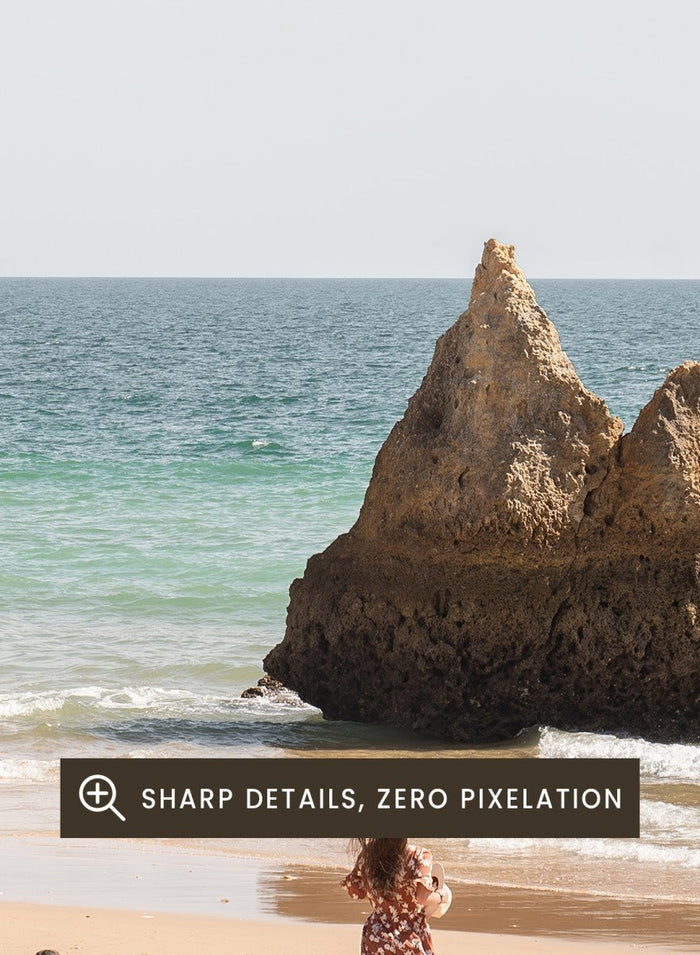 Three people on a beach with large rock formations and clear blue sky. Family Beach Day by Henrike Schenk is a coastal photography print showing a family on a sandy beach with ocean waves and dramatic sea cliffs.