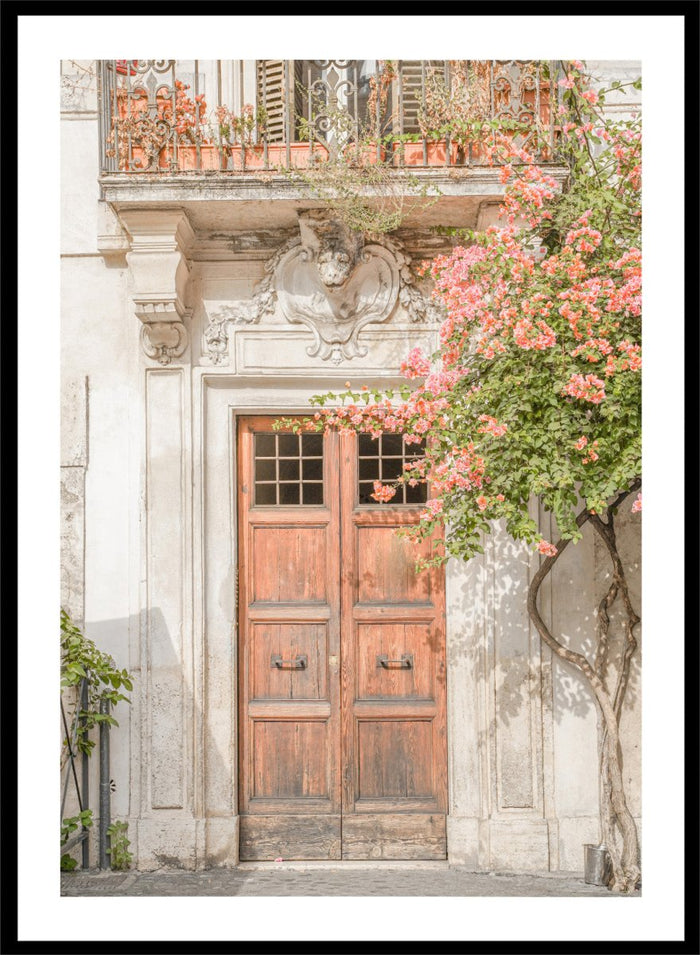 Wooden door with floral decorations on a building facade. Floral Entry by Henrike Schenk is a Mediterranean photography print featuring an old European doorway, blooming flowers, and historic architecture.