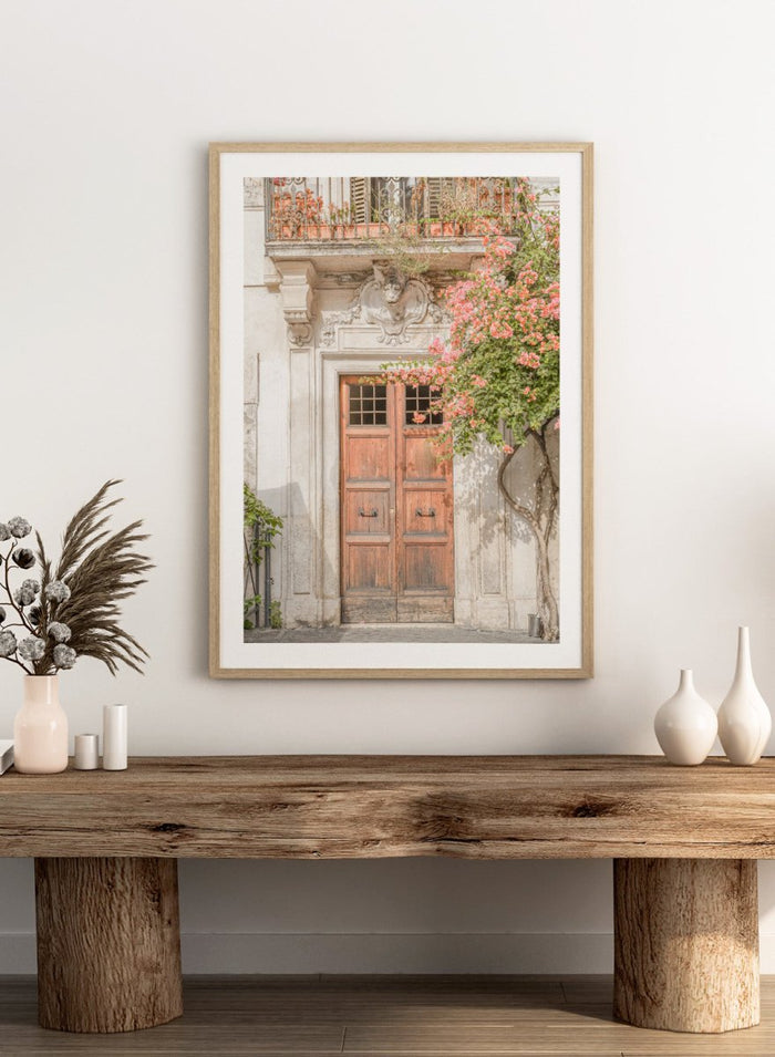 Wooden door with floral decorations on a building facade. Floral Entry by Henrike Schenk is a Mediterranean photography print featuring an old European doorway, blooming flowers, and historic architecture.