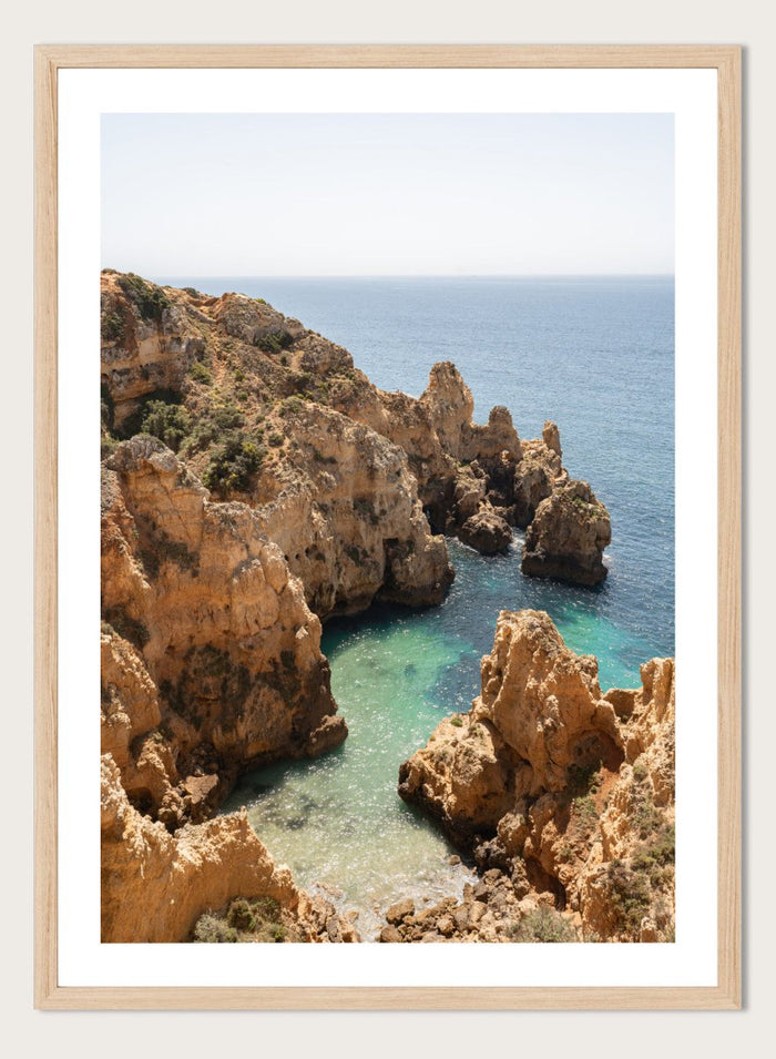 Rocky coastline with clear blue water. Golden Cliffs Azure Ocean by Henrike Schenk is a coastal photography print of rocky sea cliffs overlooking turquoise water and the Mediterranean coastline.