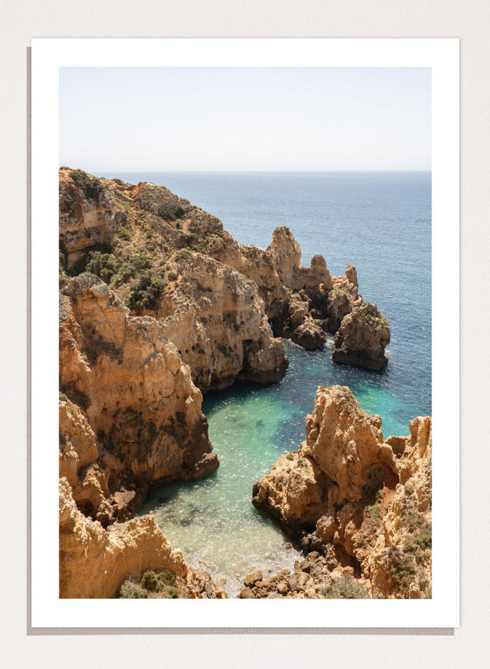 Rocky coastline with clear blue water. Golden Cliffs Azure Ocean by Henrike Schenk is a coastal photography print of rocky sea cliffs overlooking turquoise water and the Mediterranean coastline.