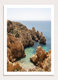 Rocky coastline with clear blue water. Golden Cliffs Azure Ocean by Henrike Schenk is a coastal photography print of rocky sea cliffs overlooking turquoise water and the Mediterranean coastline.