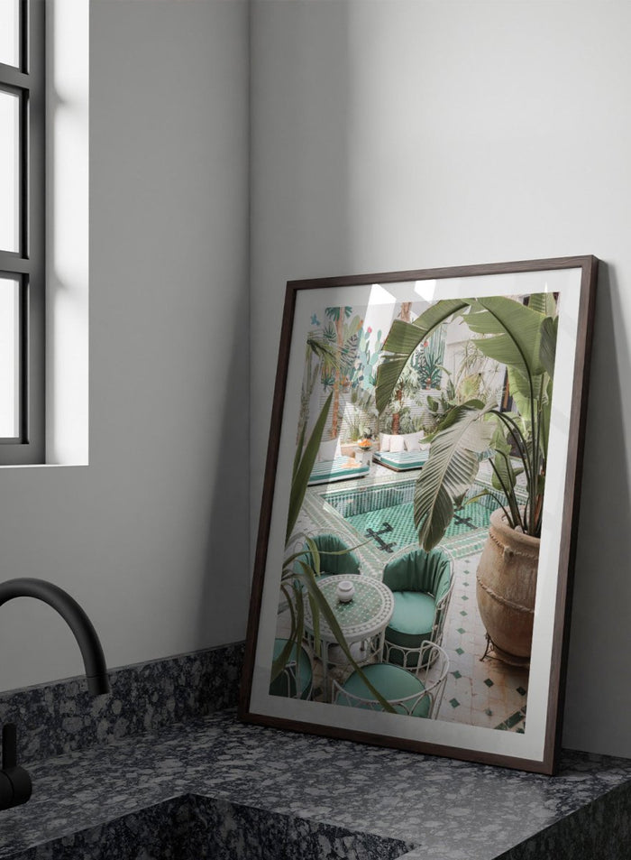 Outdoor patio with pool, green chairs, and potted plants. Green Courtyard Oasis by Henrike Schenk is a Morocco travel photography print showing a lush riad courtyard with green tilework, tropical plants, and poolside interiors.