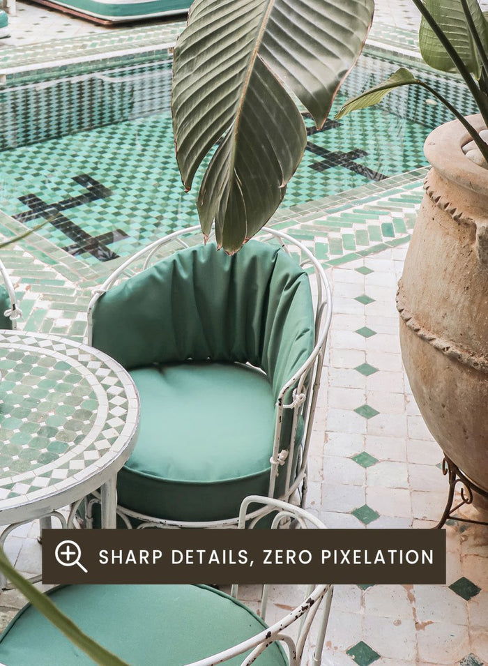 Outdoor patio with pool, green chairs, and potted plants. Green Courtyard Oasis by Henrike Schenk is a Morocco travel photography print showing a lush riad courtyard with green tilework, tropical plants, and poolside interiors.