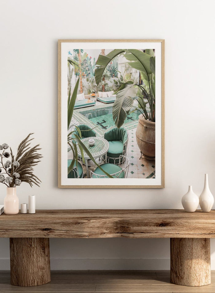 Outdoor patio with pool, green chairs, and potted plants. Green Courtyard Oasis by Henrike Schenk is a Morocco travel photography print showing a lush riad courtyard with green tilework, tropical plants, and poolside interiors.