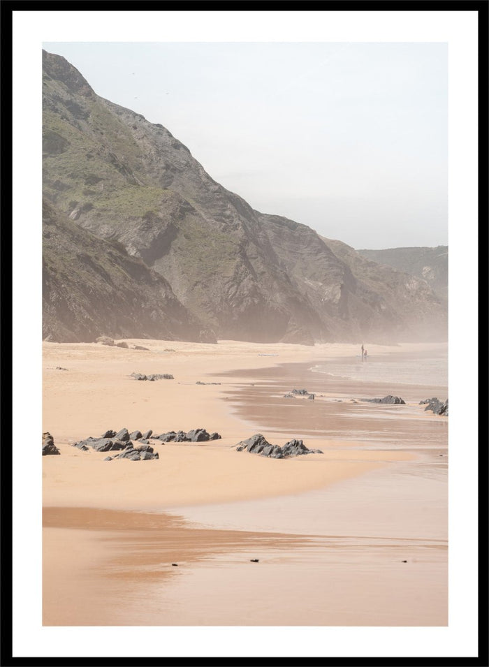 Beach scene with mountains in the background. Misty Coastal Landscape by Henrike Schenk is a coastal photography print featuring misty cliffs, sandy beaches, and a peaceful seaside landscape.