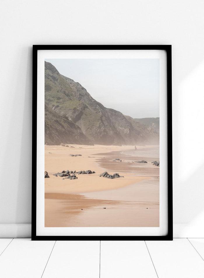 Beach scene with mountains in the background. Misty Coastal Landscape by Henrike Schenk is a coastal photography print featuring misty cliffs, sandy beaches, and a peaceful seaside landscape.