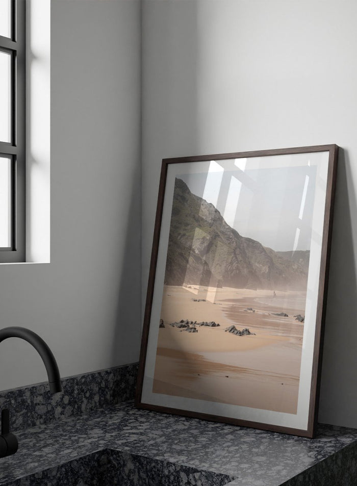 Beach scene with mountains in the background. Misty Coastal Landscape by Henrike Schenk is a coastal photography print featuring misty cliffs, sandy beaches, and a peaceful seaside landscape.
