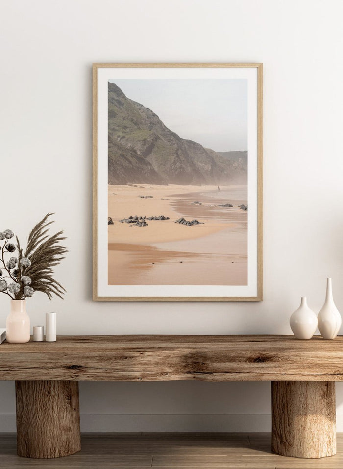 Beach scene with mountains in the background. Misty Coastal Landscape by Henrike Schenk is a coastal photography print featuring misty cliffs, sandy beaches, and a peaceful seaside landscape.