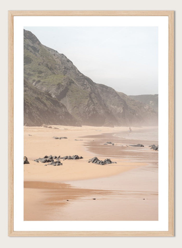 Beach scene with mountains in the background. Misty Coastal Landscape by Henrike Schenk is a coastal photography print featuring misty cliffs, sandy beaches, and a peaceful seaside landscape.
