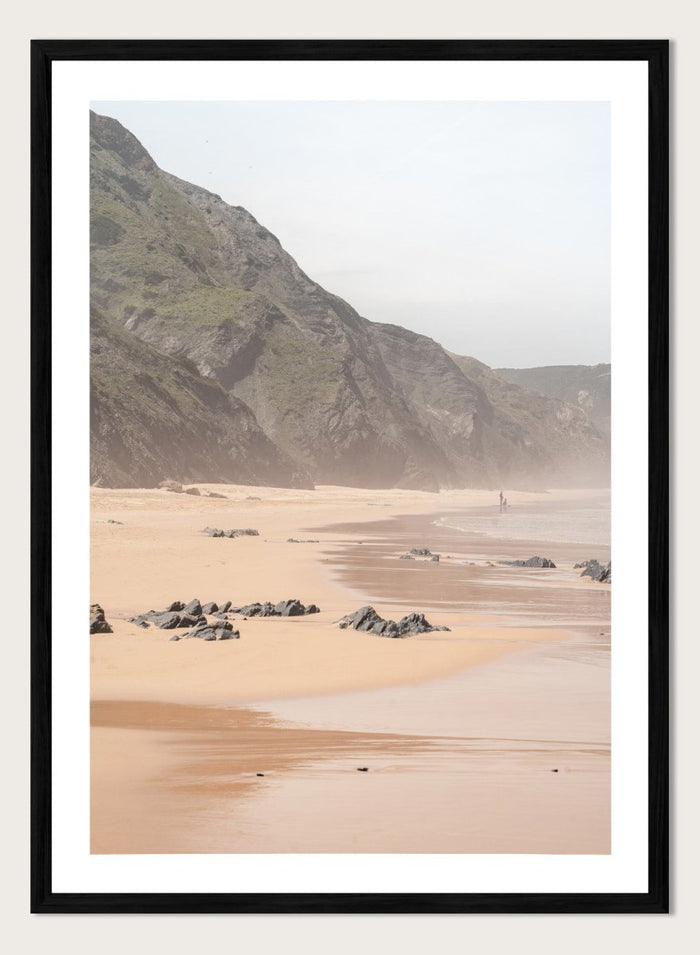 Beach scene with mountains in the background. Misty Coastal Landscape by Henrike Schenk is a coastal photography print featuring misty cliffs, sandy beaches, and a peaceful seaside landscape.