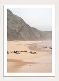 Beach scene with mountains in the background. Misty Coastal Landscape by Henrike Schenk is a coastal photography print featuring misty cliffs, sandy beaches, and a peaceful seaside landscape.