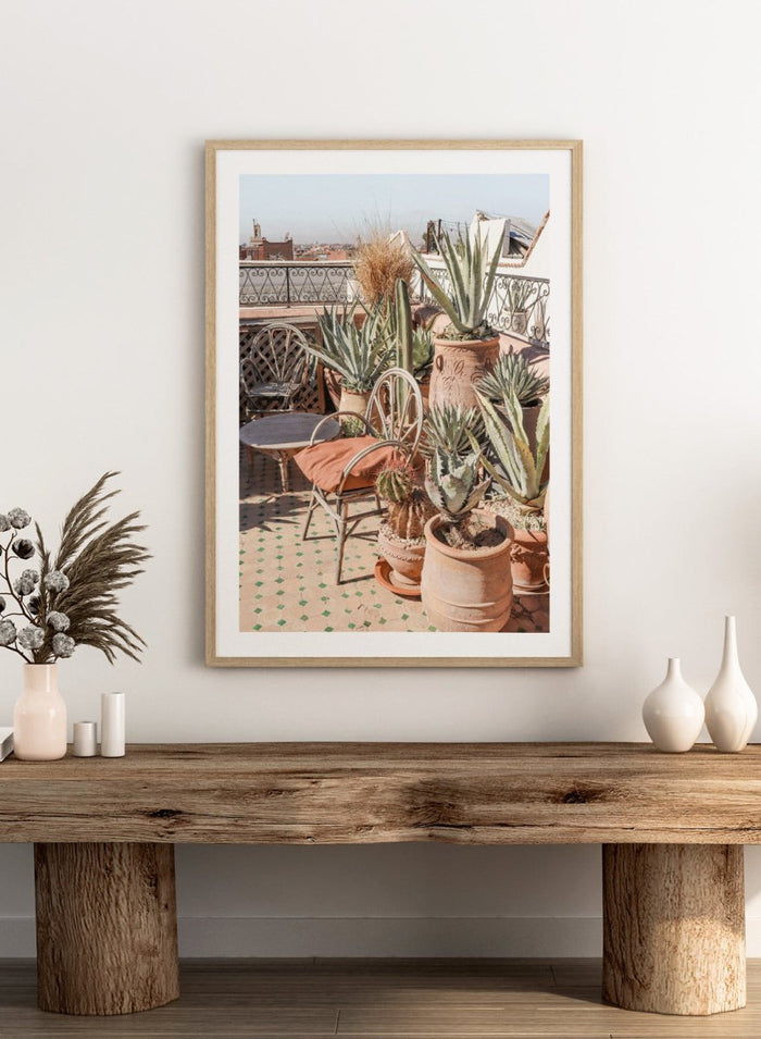 Potted plants on a balcony with a cityscape in the background. Moroccan Cactus Patio by Henrike Schenk captures a Moroccan rooftop terrace with cacti, terracotta pots, and desert-inspired photography wall art.