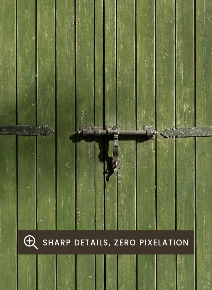 Green wooden door with metal latch on a white wall next to a pool. Moroccan Green Door by Henrike Schenk is an architectural photography print featuring green tilework, a traditional doorway, and Moroccan design details.