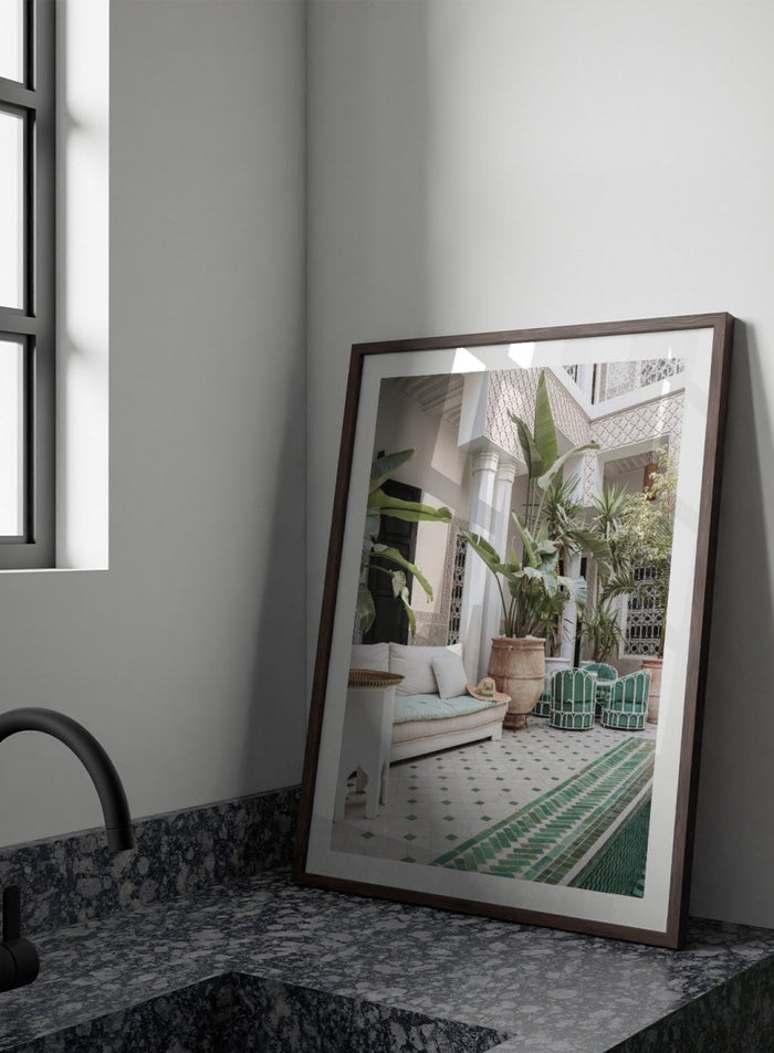 Outdoor patio with white sofa, green chairs, and potted plants in a decorative courtyard. Moroccan Riad Courtyard Oasis by Henrike Schenk is a Morocco photography print of a riad courtyard with tropical plants, tilework, and interior decor.