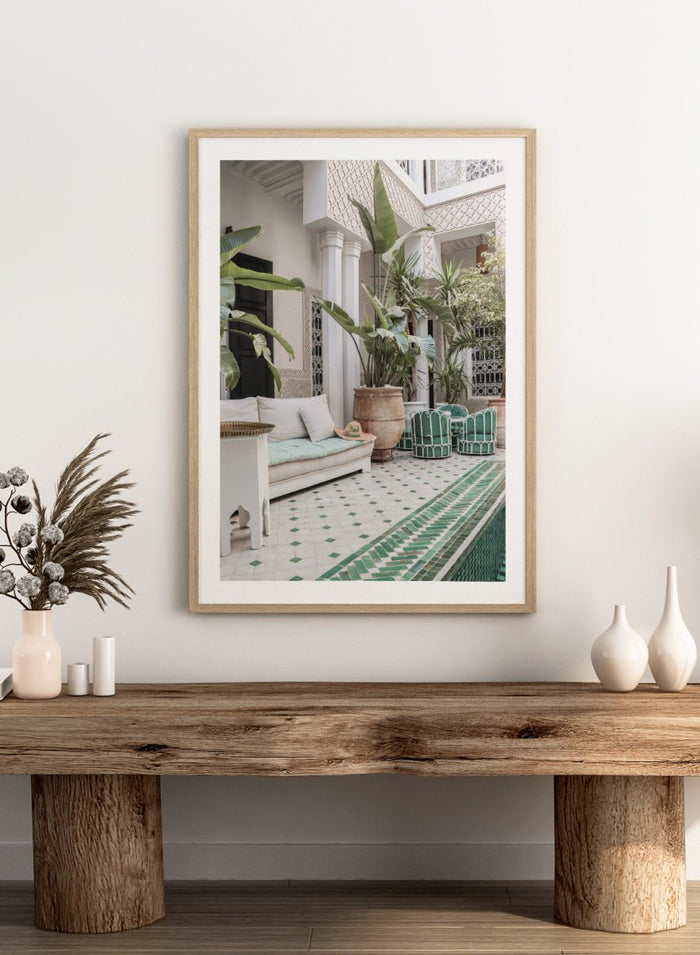 Outdoor patio with white sofa, green chairs, and potted plants in a decorative courtyard. Moroccan Riad Courtyard Oasis by Henrike Schenk is a Morocco photography print of a riad courtyard with tropical plants, tilework, and interior decor.