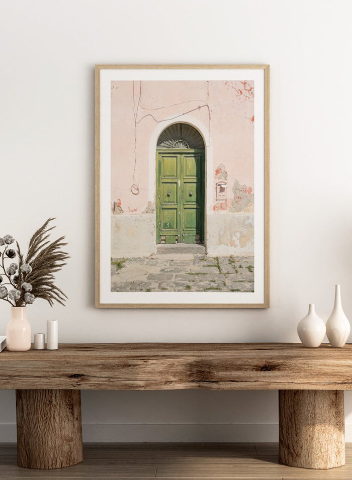 Green door on a pink wall with peeling paint. Old World Green Door by Henrike Schenk features a vintage European doorway, weathered architecture, pastel walls, travel photography, and wall art.