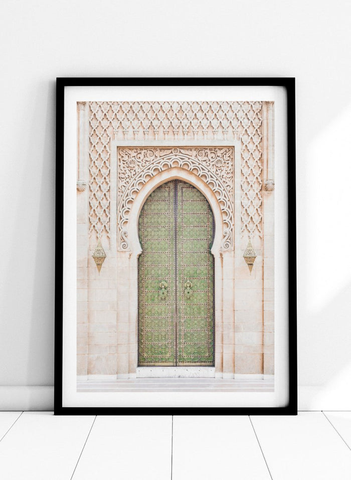 Decorative archway with ornate green door on a light stone wall. Ornate Moroccan Green Door by Henrike Schenk is a Moroccan architecture print featuring an ornate green door, Islamic patterns, and historic stone details.