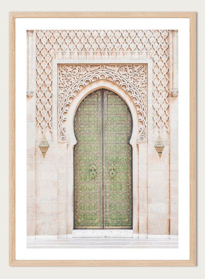 Decorative archway with ornate green door on a light stone wall. Ornate Moroccan Green Door by Henrike Schenk is a Moroccan architecture print featuring an ornate green door, Islamic patterns, and historic stone details.