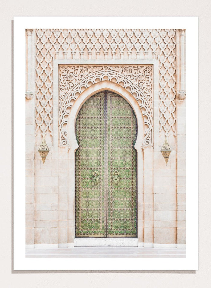 Decorative archway with ornate green door on a light stone wall. Ornate Moroccan Green Door by Henrike Schenk is a Moroccan architecture print featuring an ornate green door, Islamic patterns, and historic stone details.