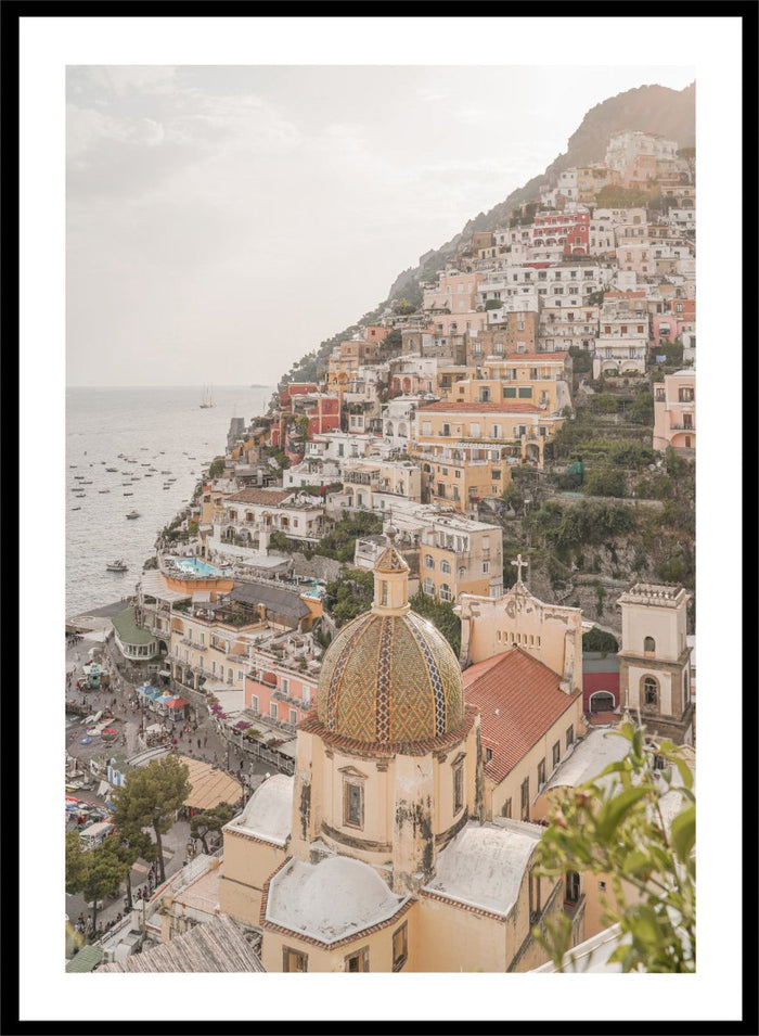 Hilly coastal town with buildings and a church dome. Positano Bliss by Henrike Schenk is a coastal photography print featuring the colorful hillside of Positano, Mediterranean architecture, and the beauty of the Amalfi Coast.