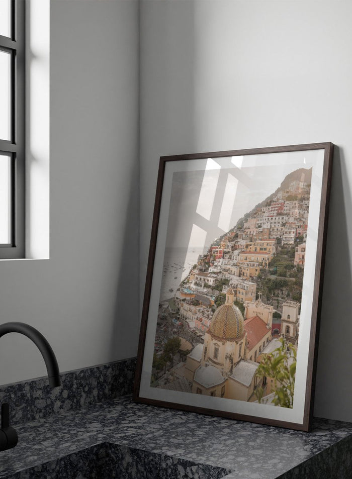 Hilly coastal town with buildings and a church dome. Positano Bliss by Henrike Schenk is a coastal photography print featuring the colorful hillside of Positano, Mediterranean architecture, and the beauty of the Amalfi Coast.