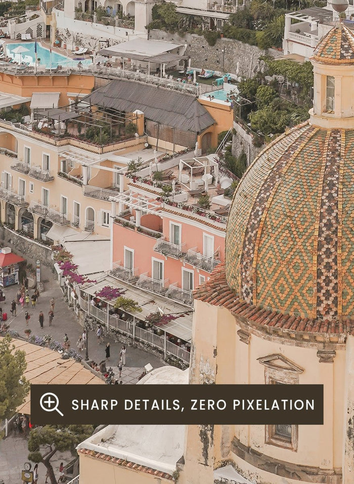 Hilly coastal town with buildings and a church dome. Positano Bliss by Henrike Schenk is a coastal photography print featuring the colorful hillside of Positano, Mediterranean architecture, and the beauty of the Amalfi Coast.