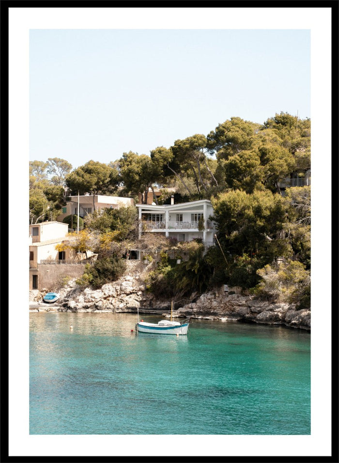 Cottage by a lake with trees and boats in the water. Serene Mediterranean Cove by Henrike Schenk is a coastal photography print featuring turquoise water, a fishing boat, seaside homes, and Mediterranean scenery.