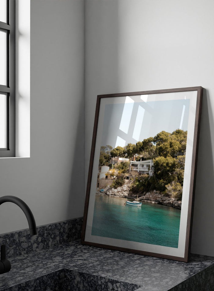 Cottage by a lake with trees and boats in the water. Serene Mediterranean Cove by Henrike Schenk is a coastal photography print featuring turquoise water, a fishing boat, seaside homes, and Mediterranean scenery.