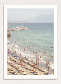 Beach scene with people and umbrellas near a body of water with mountains in the background. Summer Beach Mountain View by Henrike Schenk is a Mediterranean beach photography print featuring coastal views, mountains, ocean scenery, and summer travel.