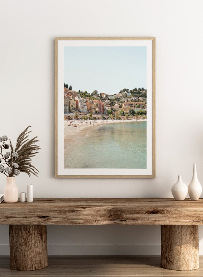 Coastal town with colorful buildings and a beach. Sunny Mediterranean Coast by Henrike Schenk is a coastal photography print featuring turquoise water, pastel buildings, Mediterranean beach scenery, and travel wall art.