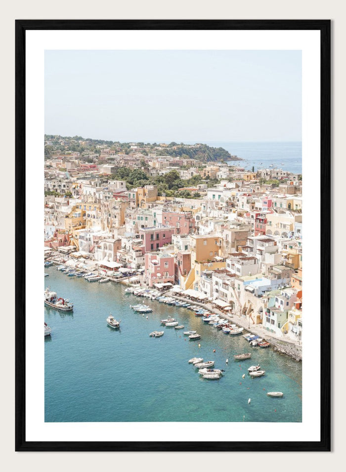 Coastal town with colorful buildings and boats in a harbor. Vibrant Italian Coastal Town by Henrike Schenk is a coastal photography print featuring pastel architecture, turquoise waters, fishing boats, and Mediterranean charm.