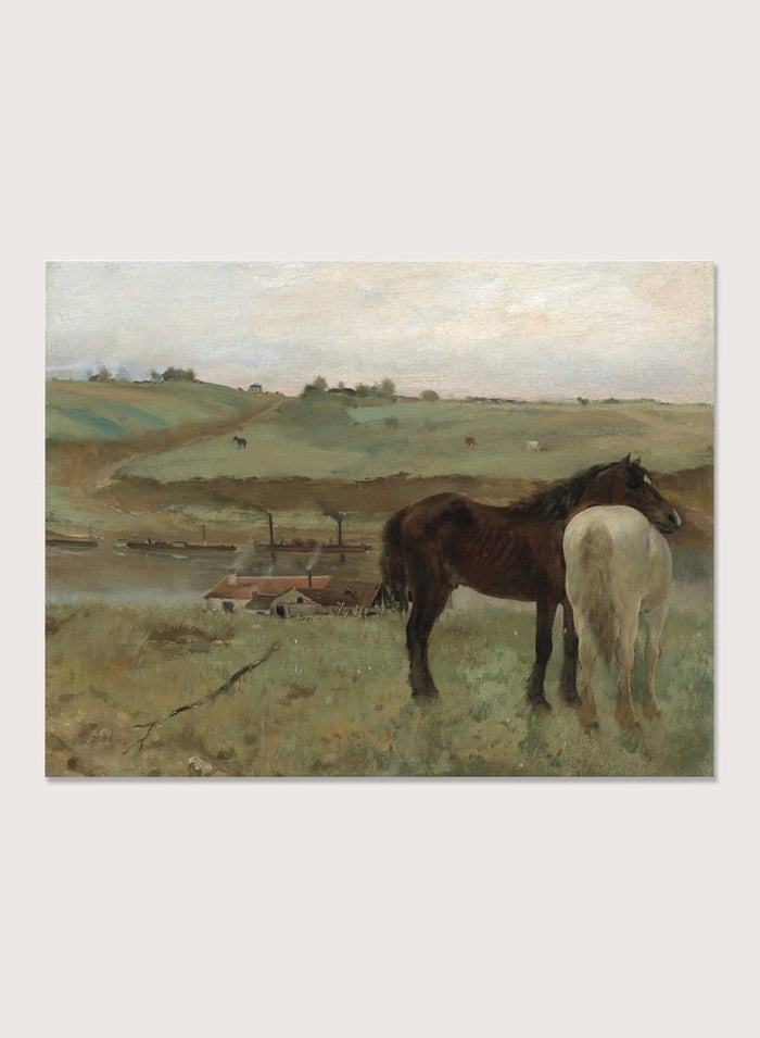 A framed landscape painting depicting two horses in a grassy field, with a muted sky and distant hills. Horses in a Meadow by Edgar Degas is a vintage horse art print featuring two horses standing together in a green field with a river, hills, and distant village.