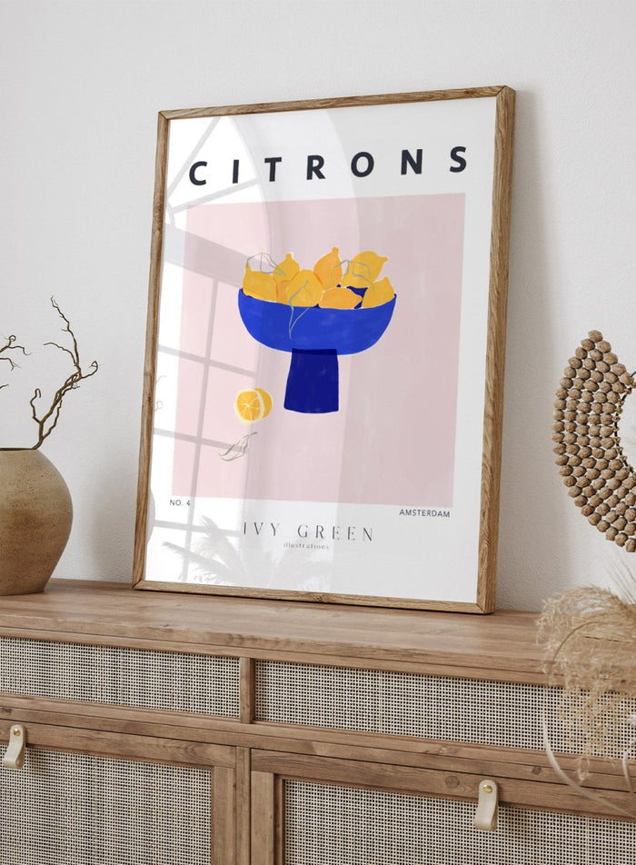 Illustration of lemons in a blue bowl on a pink background with 'Citrons' text and 'Ivy Green' branding. Citrons by Ivy Green lemon art print featuring bowl of lemons illustration, modern fruit poster design, and colorful contemporary kitchen wall art.