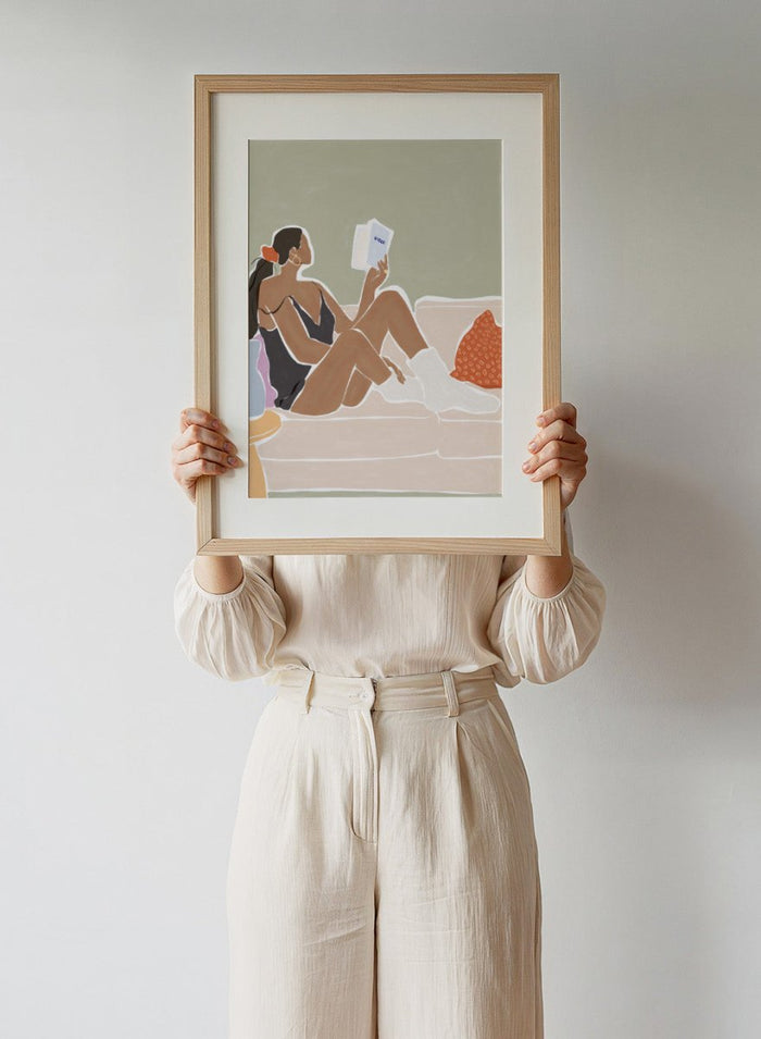 Woman Enjoying a Great Hygge Book by Ivy Green is a cozy modern figure art print celebrating slow living and self-care. Premium fine art print with optional wood framing.