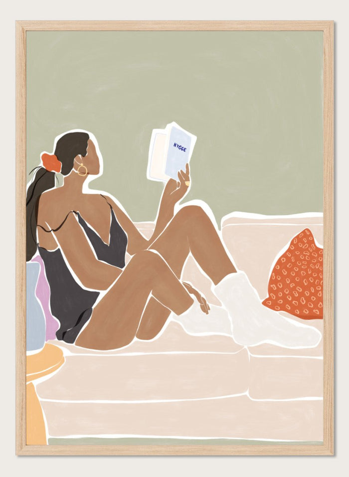 Woman Enjoying a Great Hygge Book by Ivy Green is a cozy modern figure art print celebrating slow living and self-care. Premium fine art print with optional wood framing.