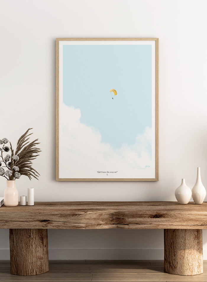 A minimalist art print featuring a light blue sky with white clouds and a small yellow-and-white parachute near the center, framed by a black border with the quote 'Did I leave the oven on?' at the bottom. Shop Paragliding Deep Thoughts by Jake Waldron, a minimalist paragliding wall art print featuring open sky, adventure humor, and soft blue and yellow tones.
