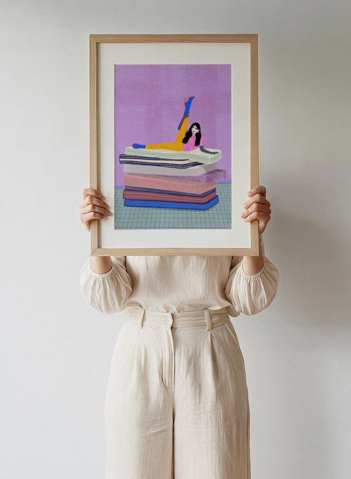 Illustration of a person sitting on a stack of books with one arm raised against a purple background. Mattress Ballet by Jota De Jai is a playful modern fine art print of a woman balancing on stacked mattresses. Available unframed or framed in real wood.
