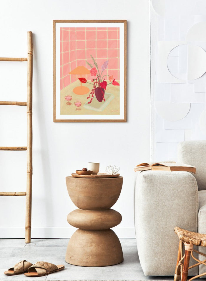 Illustration of a table with a vase of flowers, two glasses, and an orange lamp against a pink tiled wall. Bubbly by Katharina Puritscher art print featuring pink tiled walls, floral still life, coupe glasses, and a cozy tabletop scene. Officially licensed wall poster.