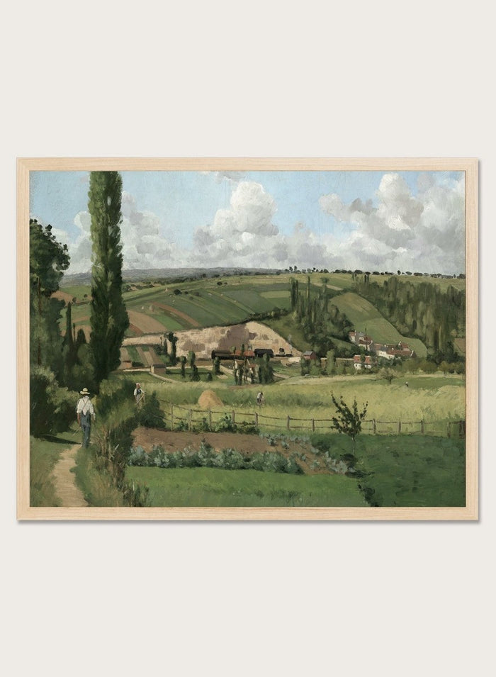 A framed landscape painting depicting a green countryside scene with rolling hills, trees, a path, small buildings, and a cloudy sky. Landscape at Les Pâtis, Pontoise by Camille Pissarro is a vintage French landscape print featuring green fields, farm workers, rolling hills, and a summer sky.