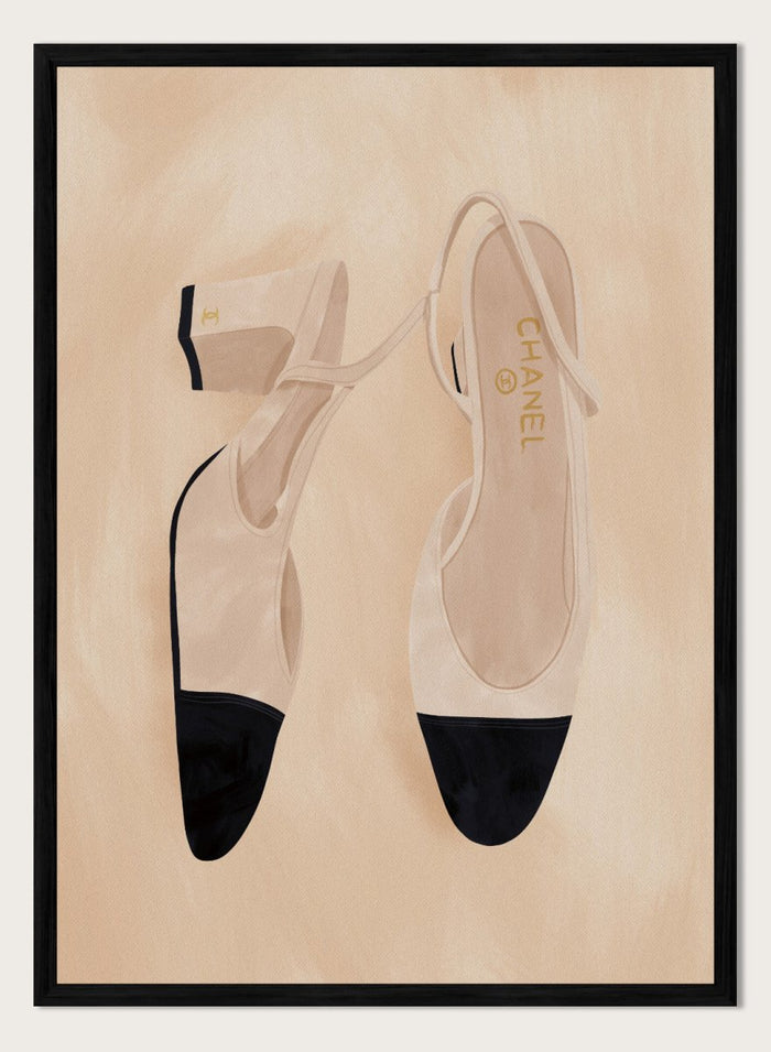 A pair of slingback flats with a beige and black color-blocked design, displayed on a textured beige background with a black border. Chic Cap-Toe Heels by Lisa Solomoniuk premium framed fine art print featuring cream slingback heels with black cap toes on a soft beige background.