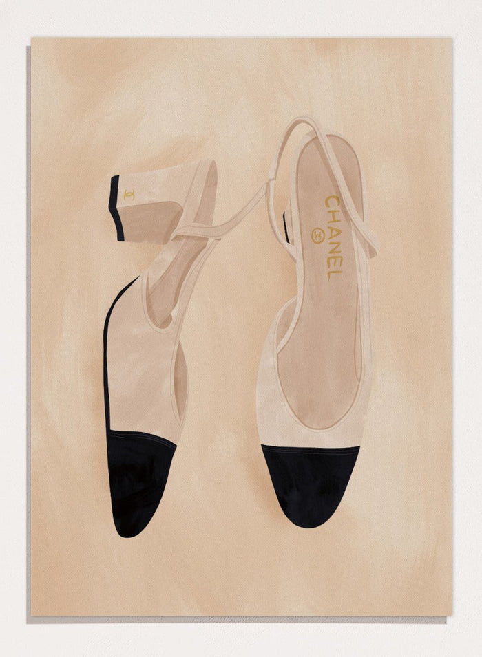 A pair of slingback flats with a beige and black color-blocked design, displayed on a textured beige background with a black border. Chic Cap-Toe Heels by Lisa Solomoniuk premium framed fine art print featuring cream slingback heels with black cap toes on a soft beige background.