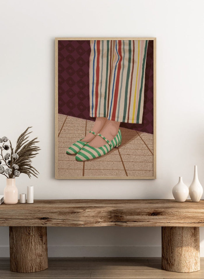 A close-up of a person's feet wearing green and white striped Mary Jane flats, paired with cream-colored striped trousers, standing on a tiled floor against a dark patterned wall. Colorful Striped Mary Janes by Lisa Solomoniuk premium framed fine art print featuring green striped shoes and colorful wide-leg trousers.