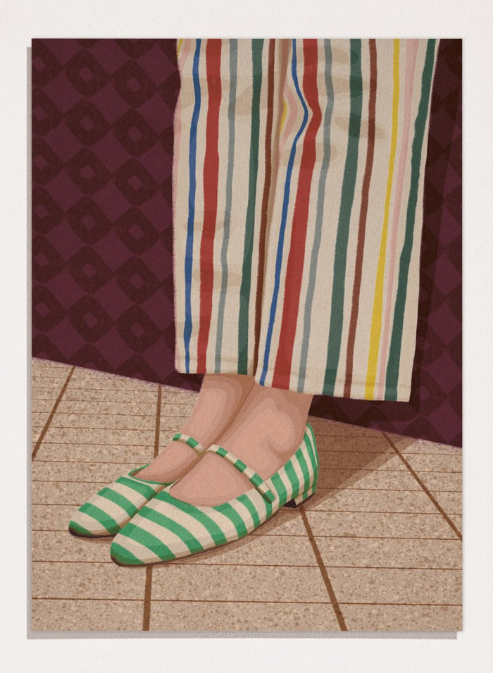 A close-up of a person's feet wearing green and white striped Mary Jane flats, paired with cream-colored striped trousers, standing on a tiled floor against a dark patterned wall. Colorful Striped Mary Janes by Lisa Solomoniuk premium framed fine art print featuring green striped shoes and colorful wide-leg trousers.